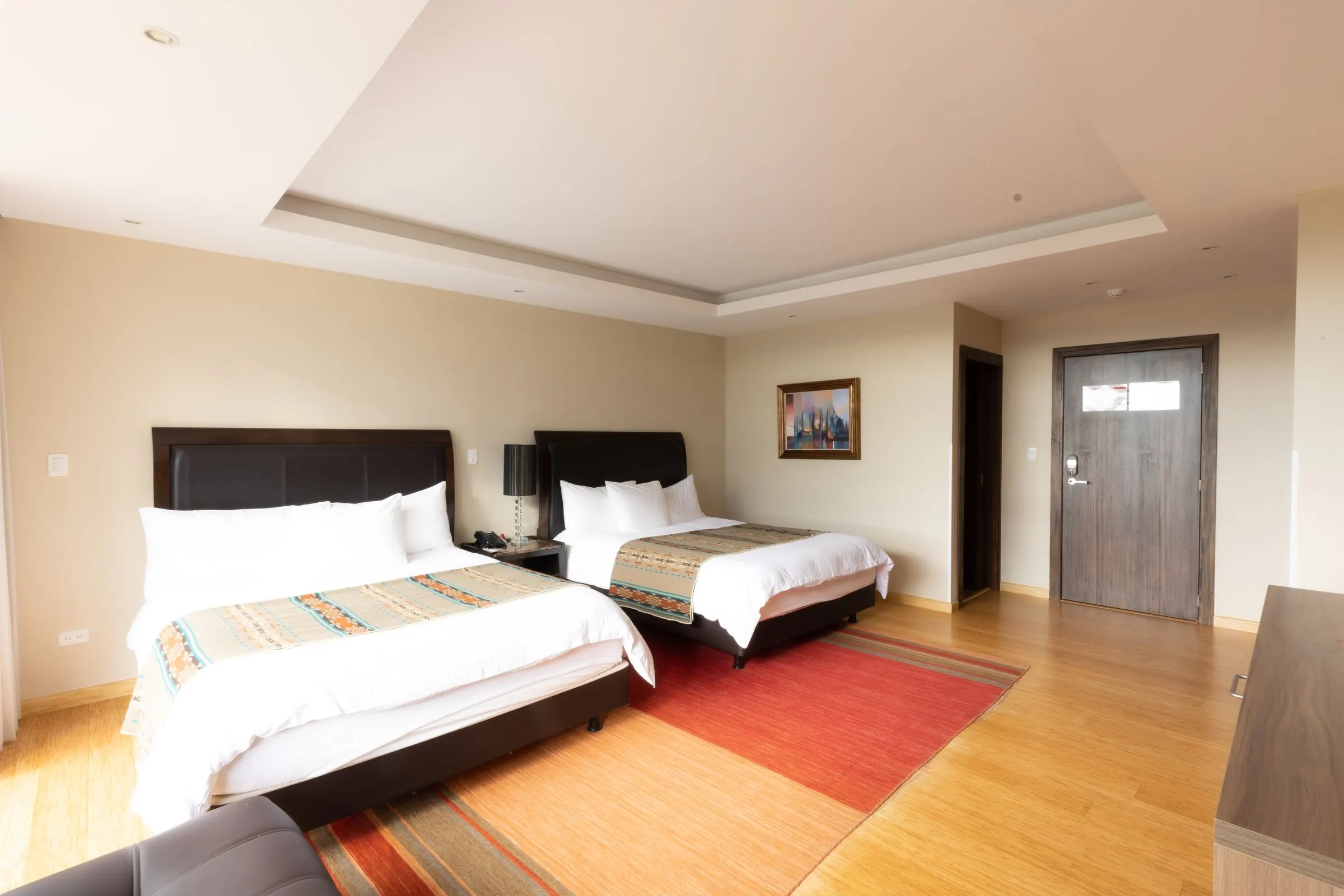 The two beds of the Double Room with a red rug and bamboo floor