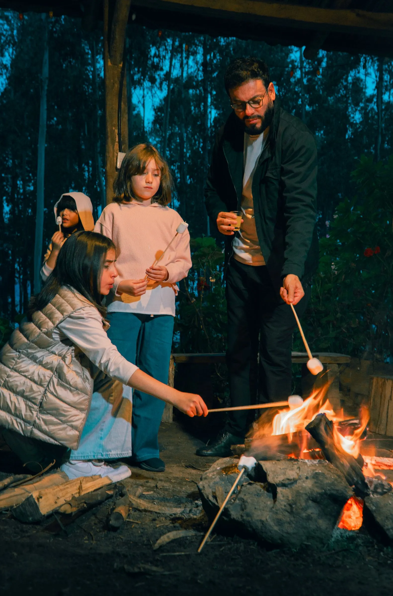Vater und Tochter rösten nachts Marshmallows am Lagerfeuer