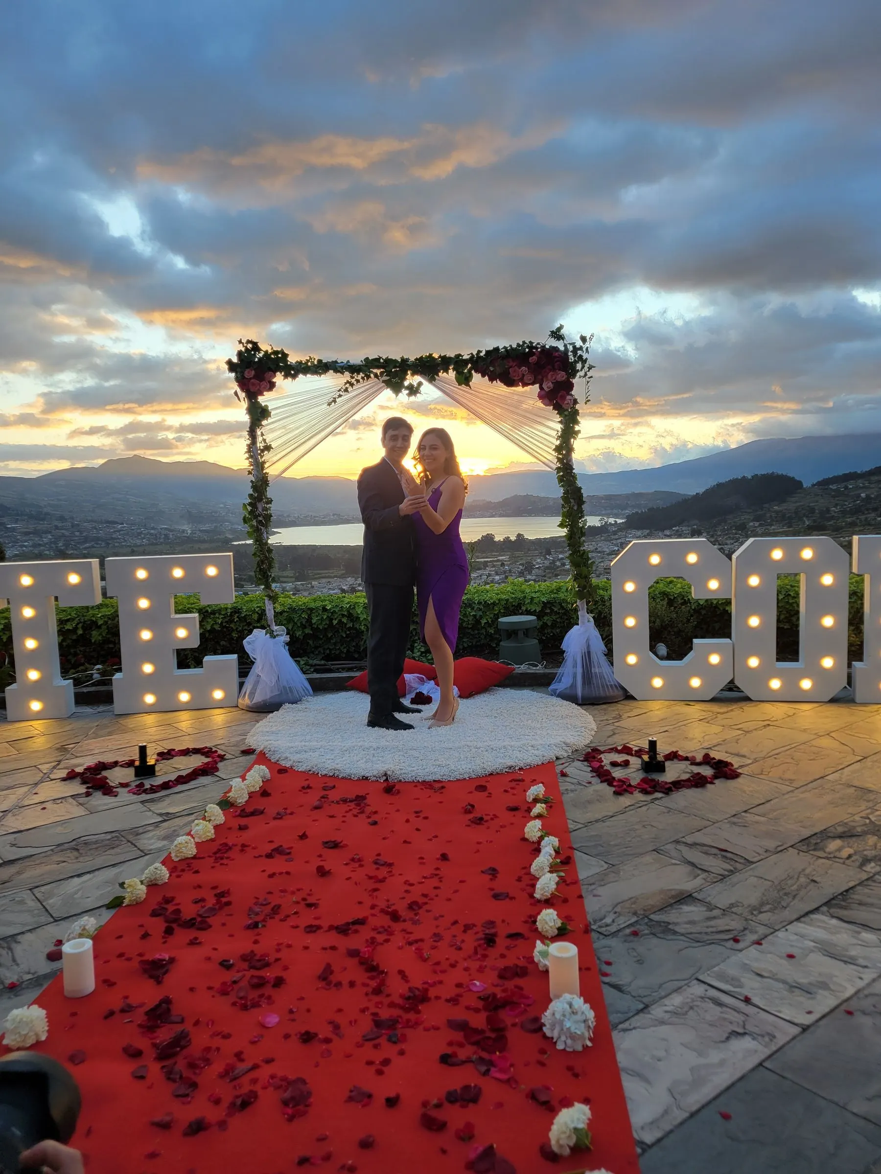 Heiratsantrag in der Abenddämmerung unter einem Bogen aus Blumen und Lichtern