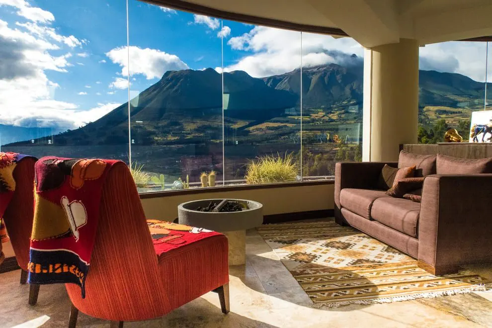 Salon mit Panoramafenster zum Imbabura, Sesseln und gewebten Teppichen