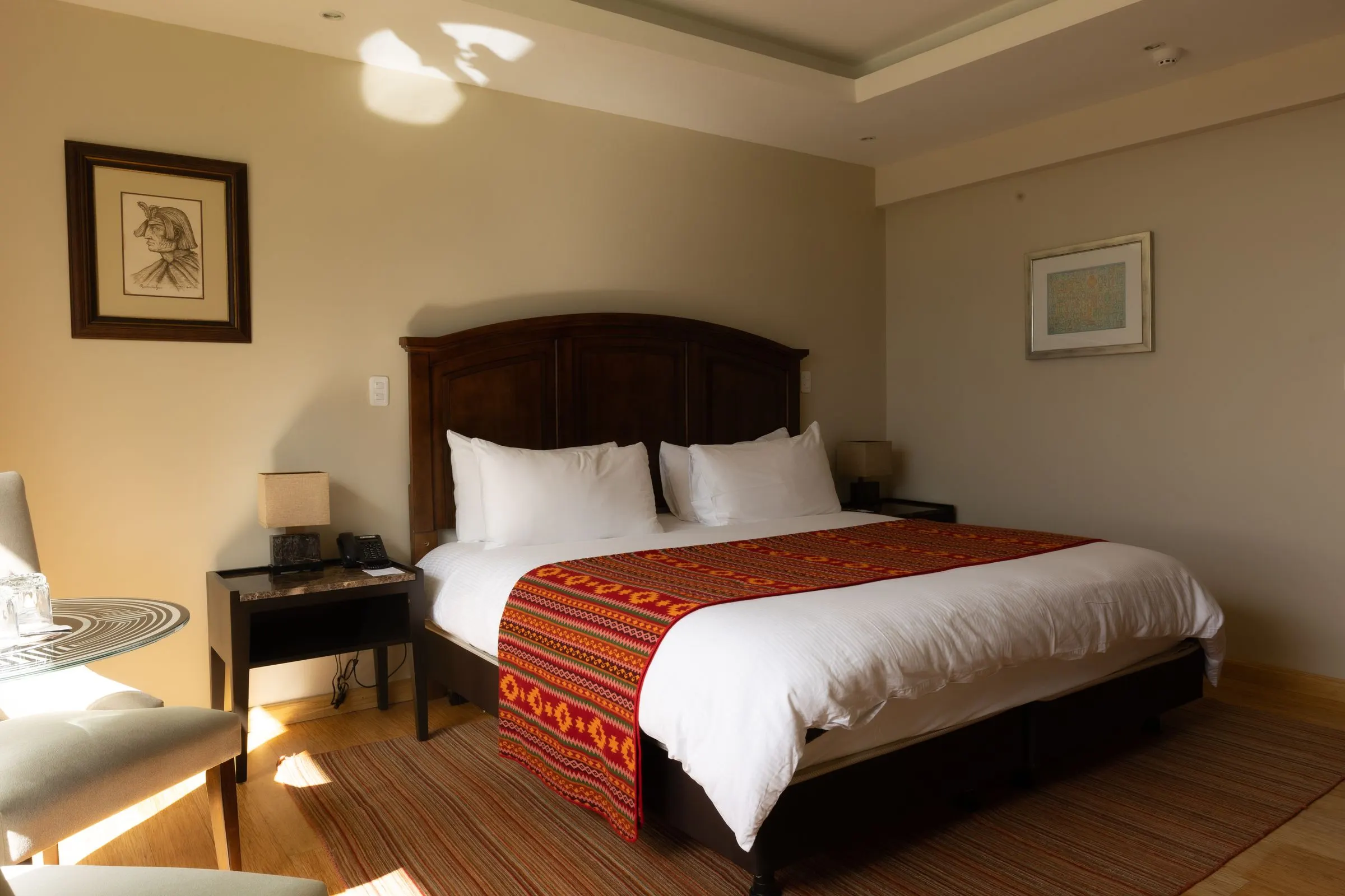 Zimmer King Standard mit weiß bezogenem Bett und Andendecke am Fußende