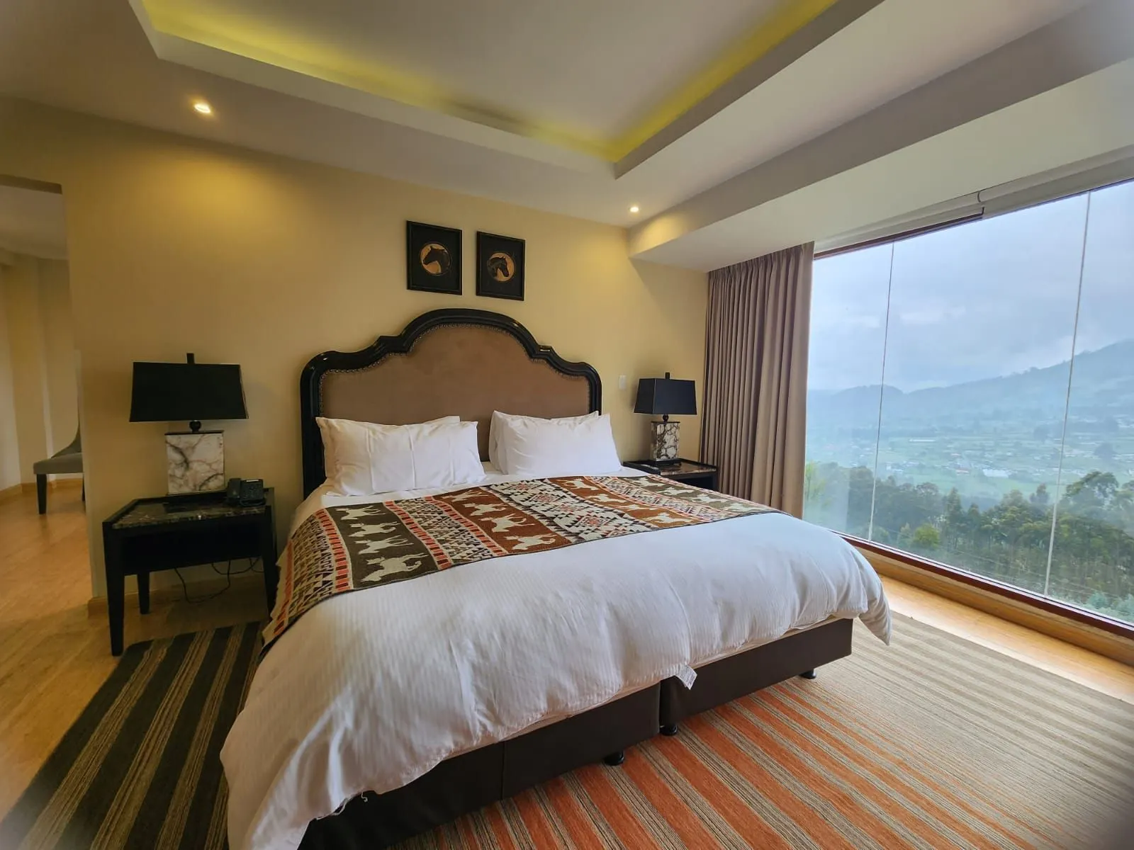Chambre de la Suite avec tête de lit capitonnée et baie vitrée sur la vallée
